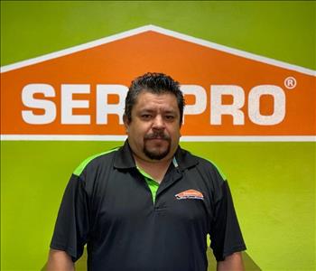 Brown haired male standing in front of a SERVPRO green background with a SERVPRO logo on the wall. 